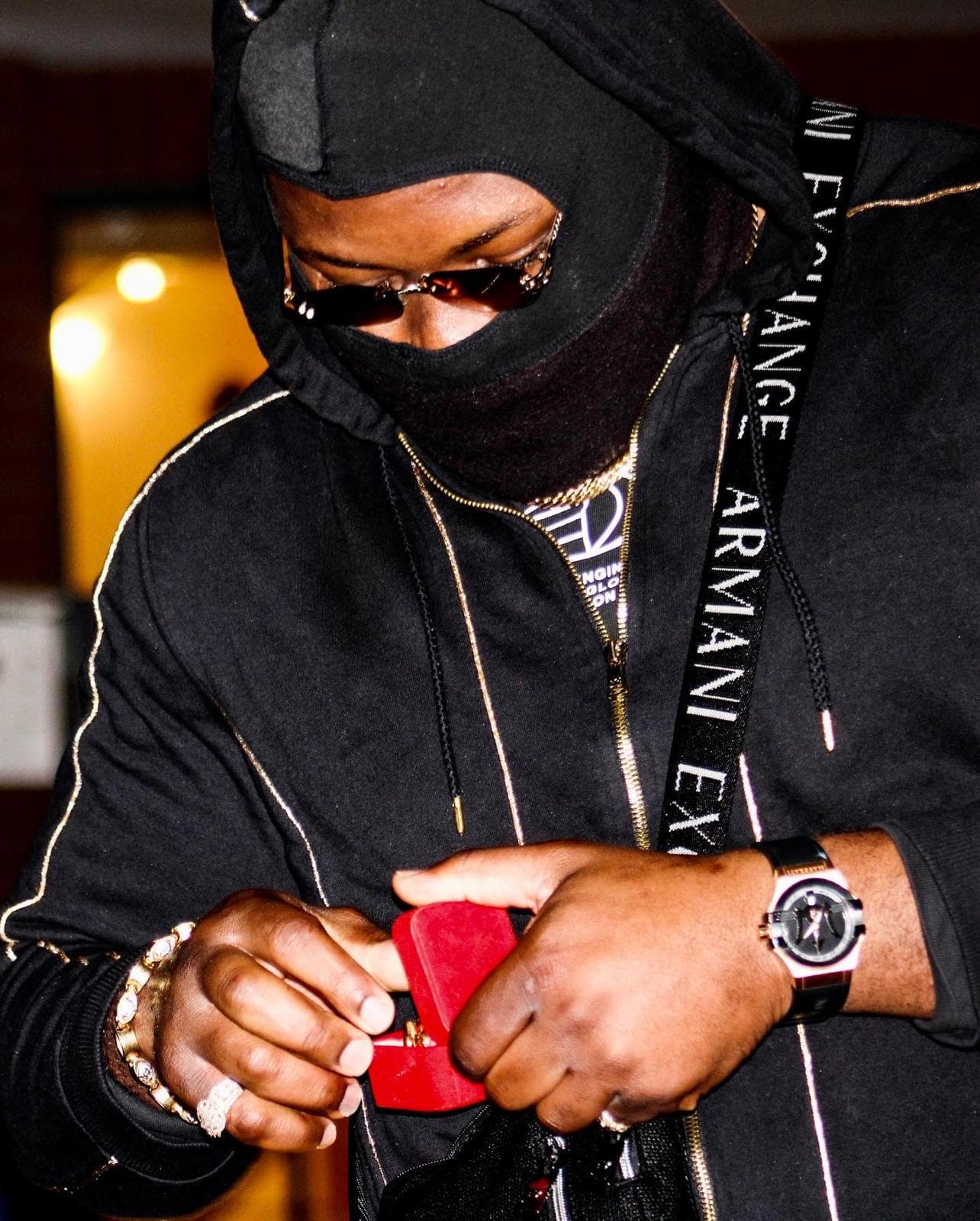j mula in a mask opening a red ring box