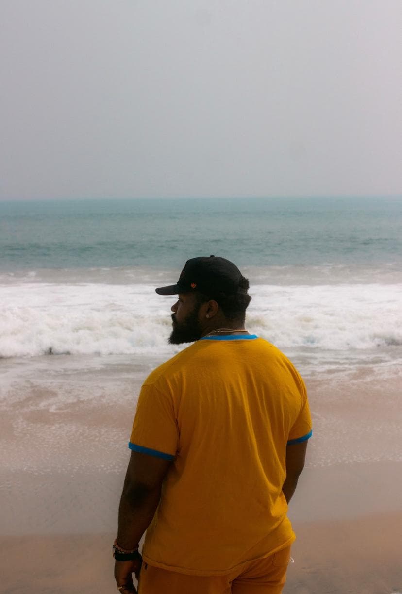 j mula with orange shirt and cap on the beach
